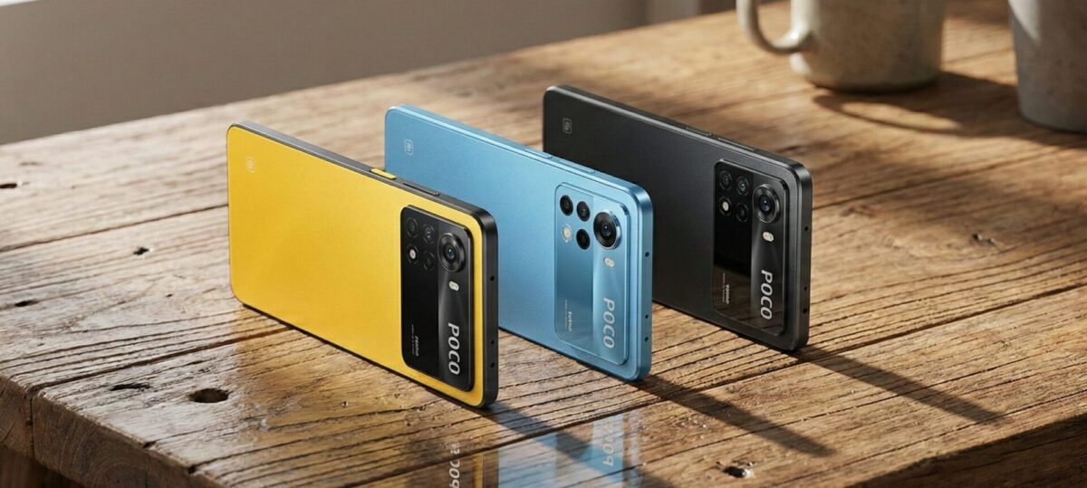 سه گوشی هوشمند پوکو در رنگهای زرد، آبی و مشکی که به صورت ایستاده روی یک میز چوبی قرار دارند.
