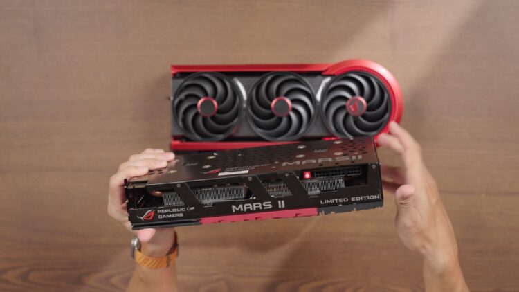 کارت گرافیک ROG Matrix با طراحی مشکی و قرمز، مجهز به سیستم خنک‌کننده سه‌فن، در حال نمایش از نمای بالا روی سطح چوبی