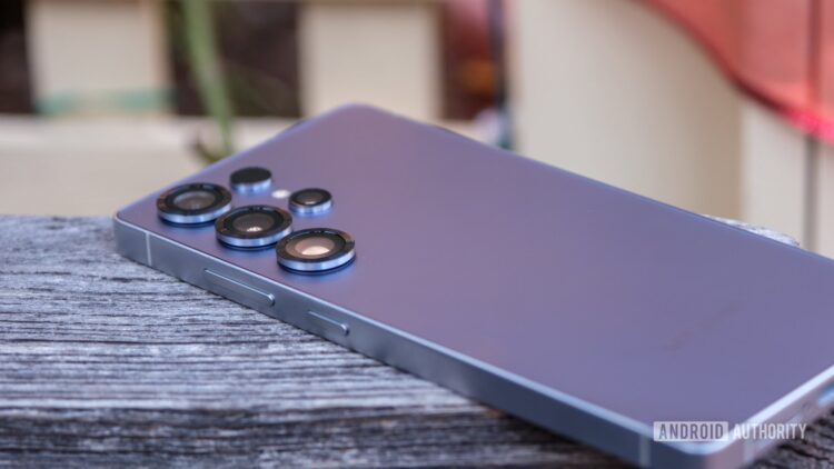 گوشی پرچمدار سامسونگ با بدنه بنفش رنگ که روی سطح چوبی قرار گرفته و لنزهای دوربین سهگانه آن دیده میشود.