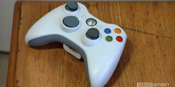 یک دسته بازی سفید و کارکردهی ایکسباکس ۳۶۰ که روی میز چوبی قرار دارد.