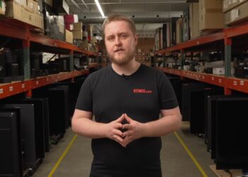 کارشناس وب‌سایت RTINGS.com در میان قفسه‌های آزمایشگاه بررسی دوام و کیفیت تلویزیون‌ها.