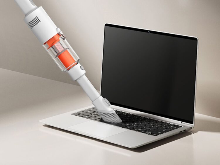 استفاده از جاروبرقی سبک و دستی شیائومی برای تمیز کردن گرد و غبار کیبورد لپتاپ.