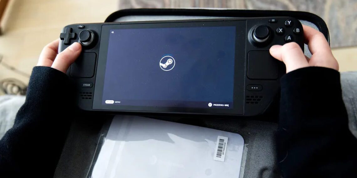 نمای نزدیک کنسول دستی Steam Deck با نمایش لوگوی Steam روی صفحه‌نمایش، طراحی کنترلرهای یکپارچه، آنالوگ‌استیک‌ها و دکمه‌های کنترلی، قرارگرفته روی سطحی نرم در محیط داخلی