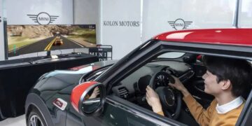 فردی در حال کار با شبیه‌ساز رانندگی مینی‌کوپر در مقابل یک مانیتور فوق‌عریض سامسونگ.