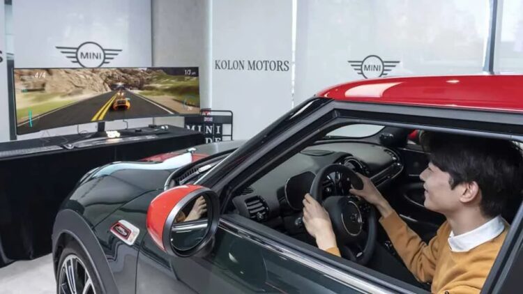 فردی در حال کار با شبیه‌ساز رانندگی مینی‌کوپر در مقابل یک مانیتور فوق‌عریض سامسونگ.