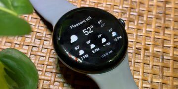 ساعت هوشمند با نمایش اطلاعات آبوهوا روی صفحه شامل دما و پیشبینی ساعتی، قرارگرفته روی سطح حصیری با بند سیلیکونی خاکستری، مناسب محتوای مرتبط با گجتهای پوشیدنی و سلامت دیجیتال