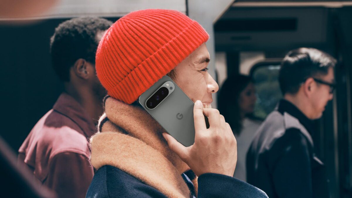 فردی در فضای شهری در حال مکالمه تلفنی با گوشی هوشمند، با پوشش زمستانی شامل کلاه بافتنی و شال، در محیط حملونقل عمومی با پسزمینه محو، مناسب محتوای سبک زندگی دیجیتال و ارتباطات موبایلی