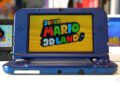کنسول دستی Nintendo 3DS با بدنه آبی، در حالت باز، با نمایش صفحه عنوان بازی Super Mario 3D Land روی نمایشگر بالایی