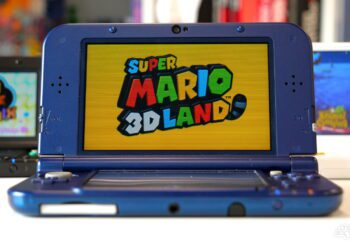 کنسول دستی Nintendo 3DS با بدنه آبی، در حالت باز، با نمایش صفحه عنوان بازی Super Mario 3D Land روی نمایشگر بالایی