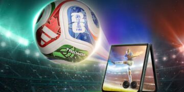 پوستر تبلیغاتی گوشی موتورولا نسخه FIFA در کنار توپ فوتبال رسمی در یک استادیوم.