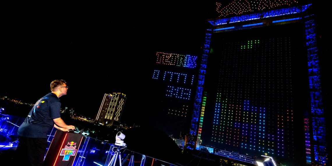 اجرای بازی تتریس زنده با پهپادهای نورانی RGB در فینال جهانی Red Bull Tetris در دبی، نمایش بلوک‌های بازی روی سازه عظیم شهری در شب
