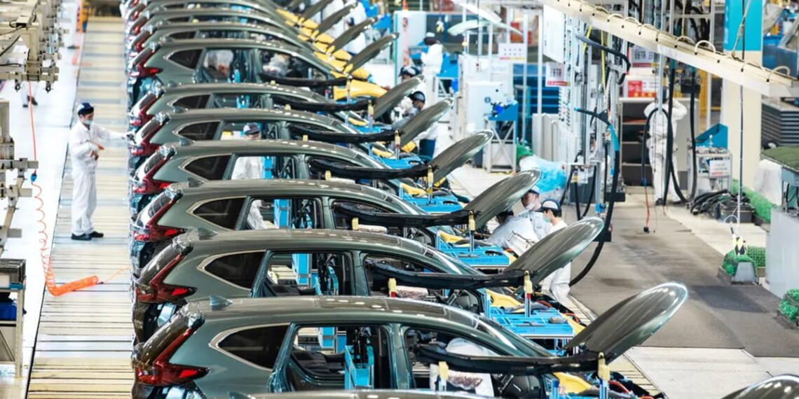 خط تولید خودرو در کارخانه صنعتی با ردیف خودروهای در حال مونتاژ، درهای باز و تجهیزات مکانیزه، نمایش فرآیند تولید انبوه و زنجیره ساخت خودروسازی