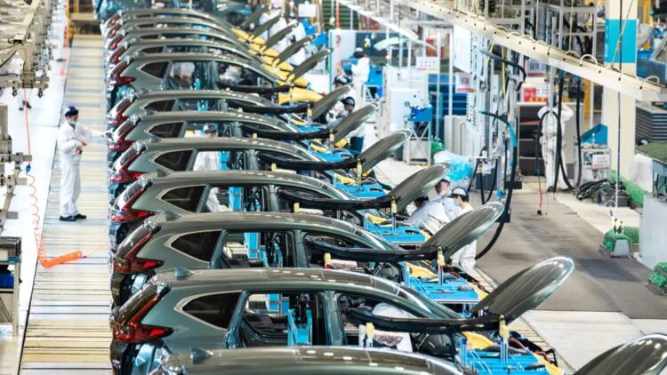 خط تولید خودرو در کارخانه صنعتی با ردیف خودروهای در حال مونتاژ، درهای باز و تجهیزات مکانیزه، نمایش فرآیند تولید انبوه و زنجیره ساخت خودروسازی