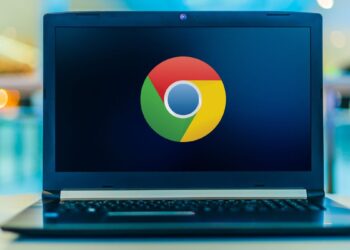 نمای لپتاپ باز با نمایش لوگوی Google Chrome در مرکز صفحهنمایش؛ دستگاه روی سطح صاف قرار دارد و پسزمینه با افکت محو رنگی، تمرکز بصری را بر برند مرورگر و استفاده دسکتاپی آن نشان میدهد.