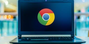 نمای لپتاپ باز با نمایش لوگوی Google Chrome در مرکز صفحهنمایش؛ دستگاه روی سطح صاف قرار دارد و پسزمینه با افکت محو رنگی، تمرکز بصری را بر برند مرورگر و استفاده دسکتاپی آن نشان میدهد.