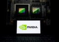 نمای نزدیک از یک تراشه گرافیکی انویدیا در کنار لپ‌تاپی که لوگوی NVIDIA را نمایش می‌دهد.