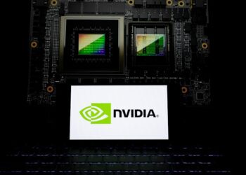 نمای نزدیک از یک تراشه گرافیکی انویدیا در کنار لپ‌تاپی که لوگوی NVIDIA را نمایش می‌دهد.