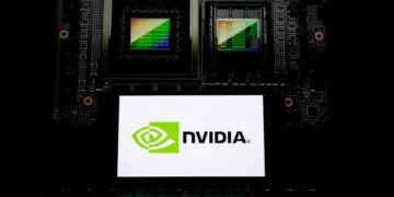 نمای نزدیک از یک تراشه گرافیکی انویدیا در کنار لپتاپی که لوگوی NVIDIA را نمایش میدهد.