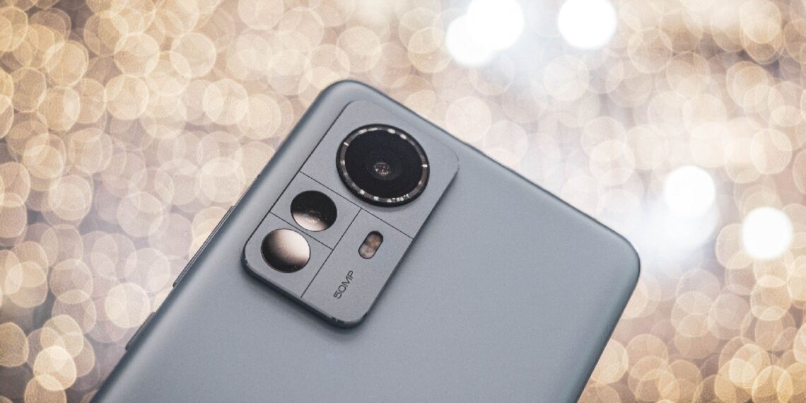 نمای نزدیک از پنل پشتی یک گوشی هوشمند خاکستری رنگ (احتمالاً سری شیائومی ۱۲) که ماژول دوربین سهگانه و عبارت 50MP روی آن دیده میشود.