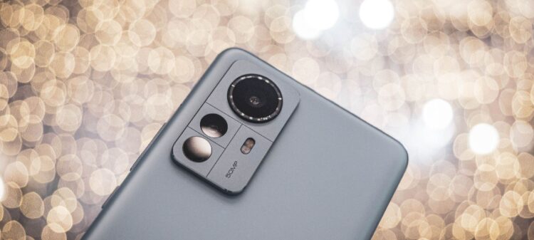 نمای نزدیک از پنل پشتی یک گوشی هوشمند خاکستری رنگ (احتمالاً سری شیائومی ۱۲) که ماژول دوربین سه‌گانه و عبارت 50MP روی آن دیده می‌شود.