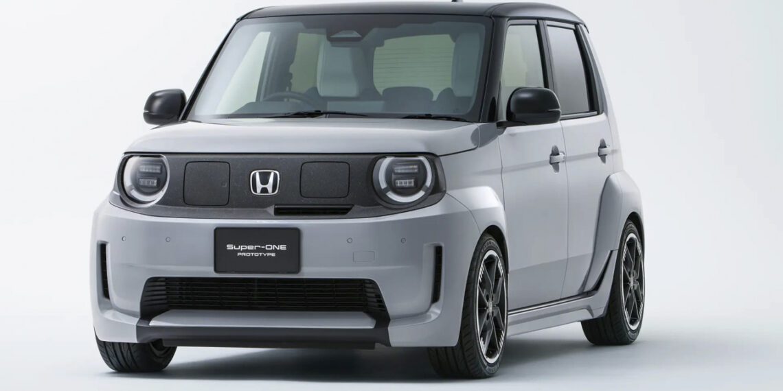 نمای سه‌رخ جلو خودروی برقی هوندا سوپر-وان ۲۰۲۶ با بدنهٔ خاکستری، طراحی جعبه‌ای، چراغ‌های گرد LED و رینگ‌های اسپرت مشکی در پس‌زمینهٔ استودیویی سفید