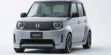 نمای سهرخ جلو خودروی برقی هوندا سوپر-وان ۲۰۲۶ با بدنهٔ خاکستری، طراحی جعبهای، چراغهای گرد LED و رینگهای اسپرت مشکی در پسزمینهٔ استودیویی سفید