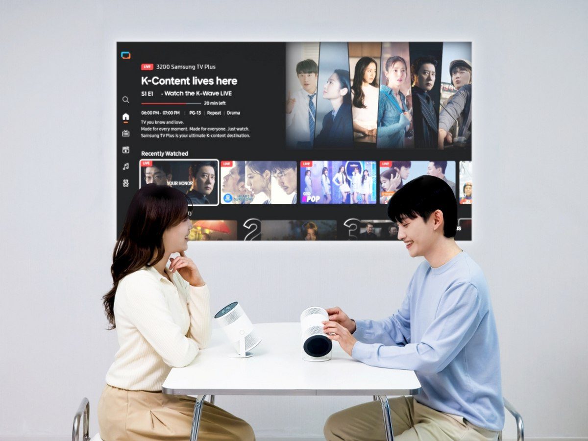 کاربری که در حال تنظیم دو عدد پروژکتور قابل حمل Samsung The Freestyle روی میز سفید است.