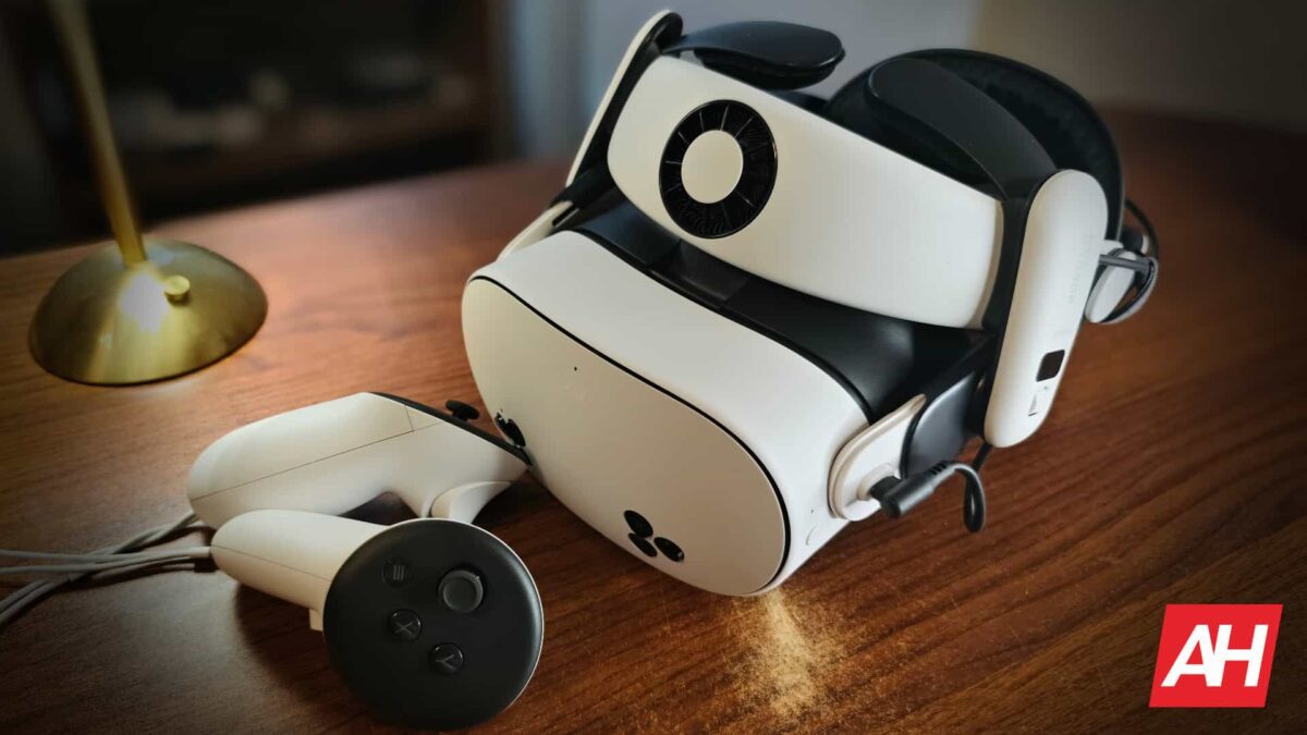 نمای نزدیک از هدست واقعیت مجازی سفید Meta Quest 3S به همراه بند نگهدارنده BoboVR و دسته‌های کنترلی روی میز چوبی.