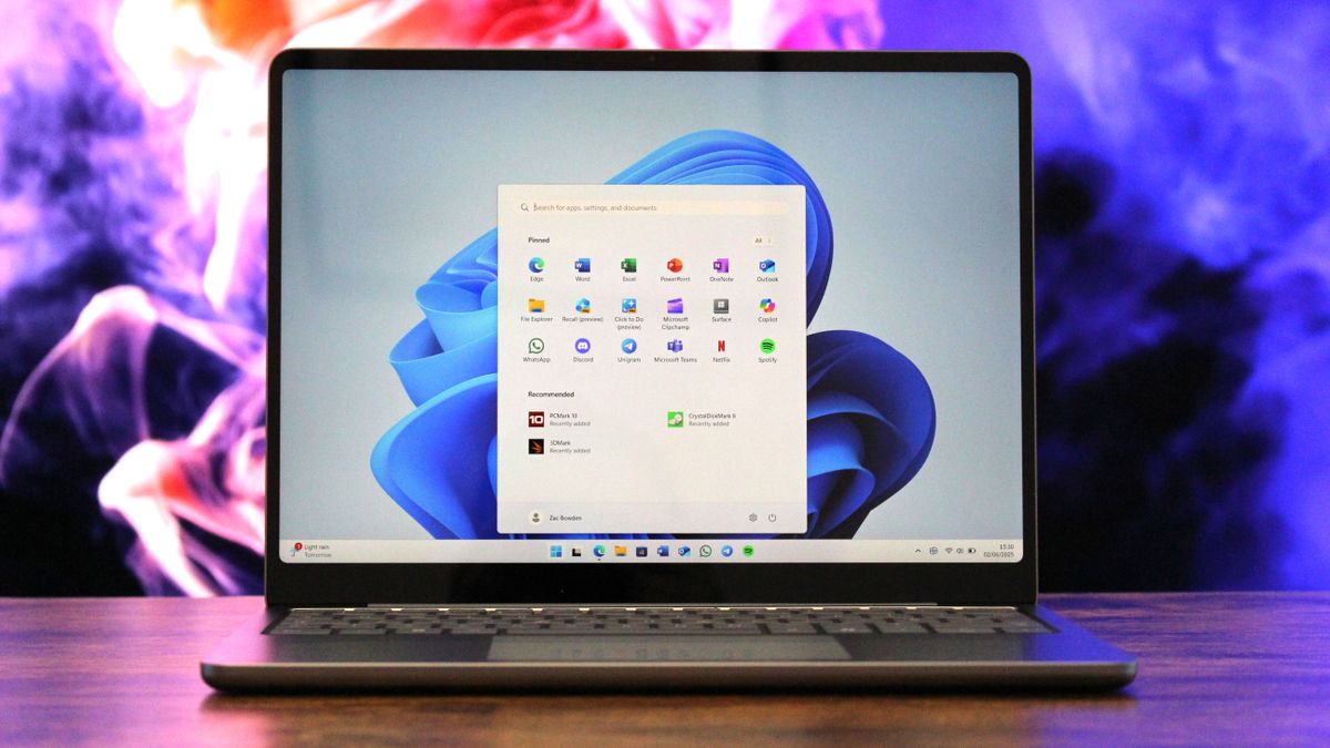 نمای نزدیک از صفحه نمایش لپ‌تاپ که منوی استارت باز شده ویندوز ۱۱ و آیکون‌های برنامه‌های مختلف را نشان می‌دهد.