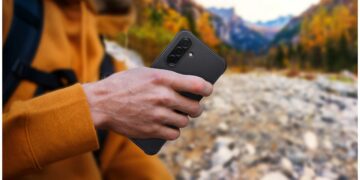 فردی در طبیعت که گوشی هوشمندی با قاب محافظ مشکی و مقاوم در دست دارد.