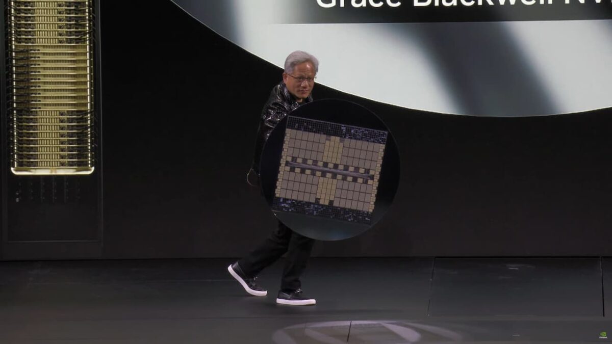جنسن هوانگ، مدیرعامل انویدیا، روی صحنه در حال نمایش یک ویفر بزرگ از تراشه‌های Blackwell.