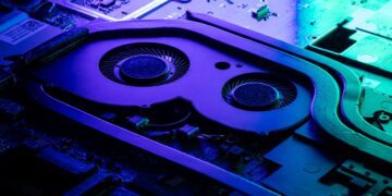 نمای نزدیک از سیستم خنککننده داخلی لپتاپ با نورپردازی بنفش و سبز.