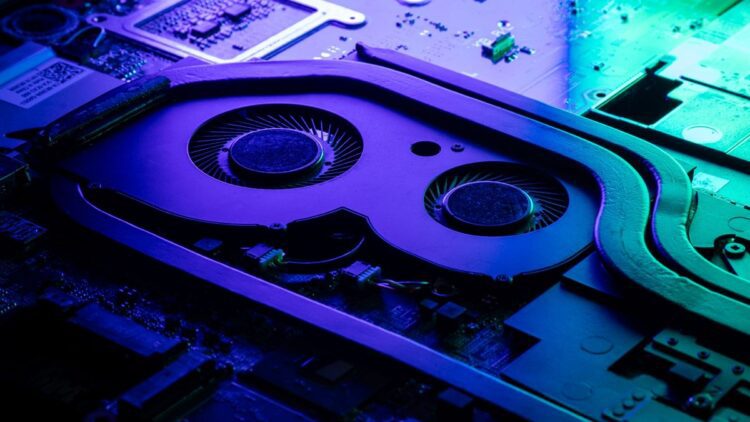 نمای نزدیک از سیستم خنک‌کننده داخلی لپ‌تاپ با نورپردازی بنفش و سبز.