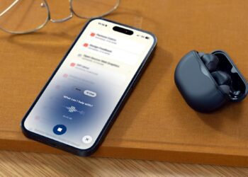 هدفونهای بیسیم Subtle Voicebuds در کنار گوشی آیفون که در حال نمایش رابط کاربری چت هوش مصنوعی و ضبط صدا است.