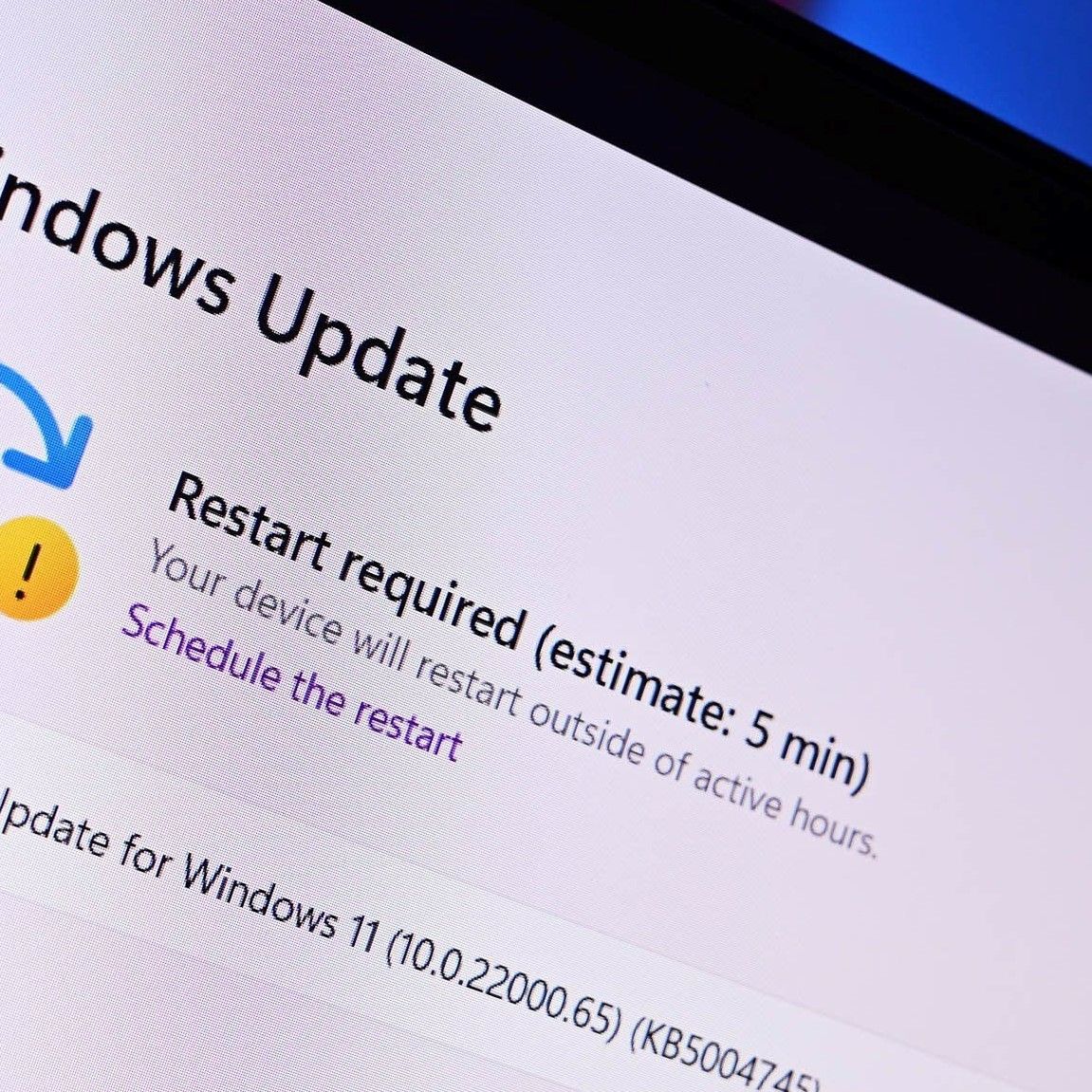 تصویر نزدیک از مانیتور که پیغام "Restart required" برای آپدیت ویندوز ۱۱ را نشان میدهد.