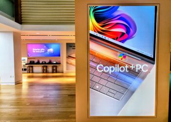استند تبلیغاتی در یک فروشگاه که لپ‌تاپی با عنوان "Copilot+ PC" را نمایش می‌دهد.