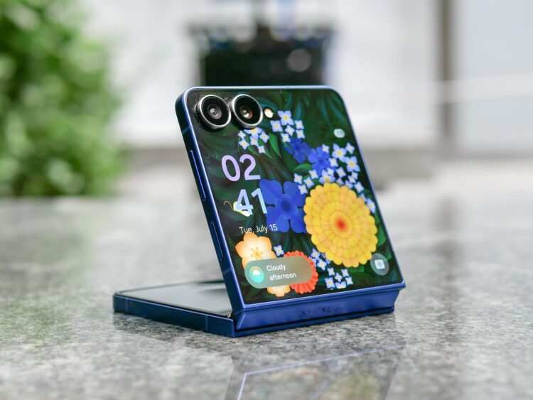 گوشی تاشوی عمودی با طراحی صدفی در حالت نیمهباز روی سطح سنگی، نمایش صفحهنمایش با والپیپر گلدار، ساعت و ویجت هواشناسی، بههمراه ماژول دوربین دوگانه در گوشه بالا