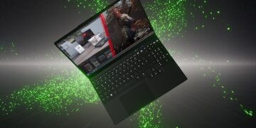 لپتاپ گیمینگ مشکی TUXEDO در حالت معلق با پسزمینه ذرات سبز درخشان که بازی Black Myth: Wukong را نمایش میدهد.