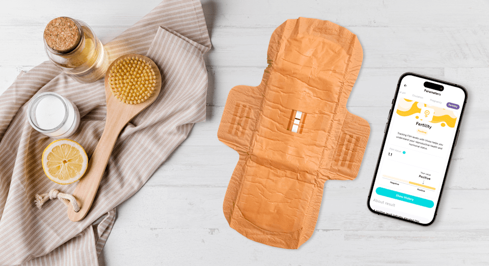 پد بهداشتی هوشمند Vivoo در کنار یک تلفن همراه که نتایج تست باروری و هورمونی را نمایش می‌دهد.