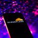 تصویر مفهومی از یک تلفن هوشمند با نمایش لوگوی Cloudflare روی صفحه‌نمایش. پس‌زمینه شامل شبکه‌ای انتزاعی از نقاط و خطوط نورانی به رنگ‌های بنفش و آبی است که مفاهیم زیرساخت شبکه، امنیت ابری و ترافیک داده را القا می‌کند.