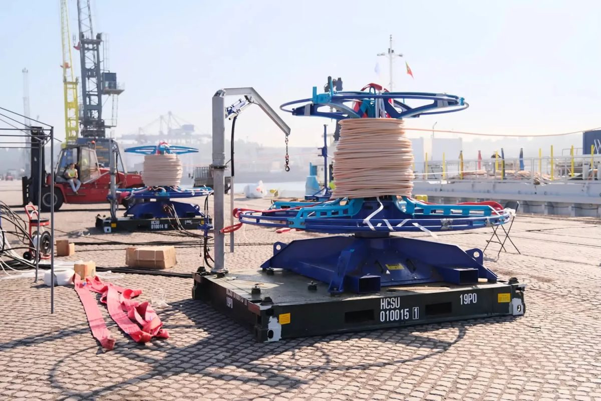 تجهیزات صنعتی نصب کابل زیردریایی در بندر، شامل قرقرههای بزرگ کابل فیبر نوری و ماشینآلات مخصوص آمادهسازی زیرساخت ارتباطی دریایی