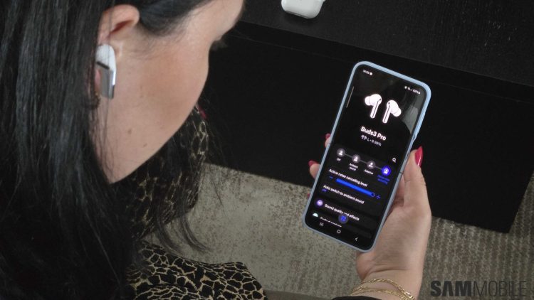 زنی که هندزفری Galaxy Buds Pro را در گوش دارد و در حال کار با اپلیکیشن مدیریت آن در گوشی است.