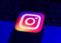 نمای نزدیک و تار از لوگوی رنگارنگ اینستاگرام بر روی صفحه نمایش یک گوشی هوشمند.