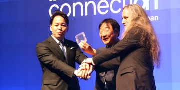 سه مدیر اجرایی بر روی صحنه که یک نمونه اولیه کوچک از حافظه ZAM را به دوربین نشان می‌دهند.