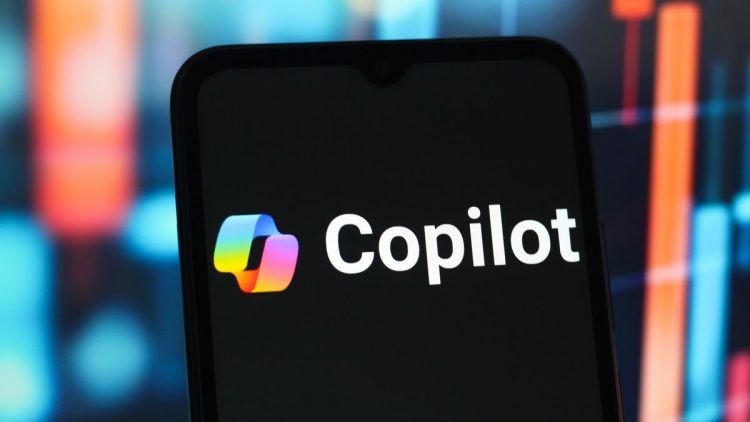 نمای نزدیک از صفحه یک گوشی هوشمند که لوگوی رنگی و متن سفید Microsoft Copilot را نمایش می‌دهد.