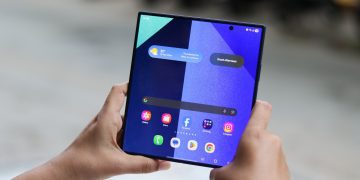 نمای نزدیک از یک گوشی تاشو سامسونگ در حالت باز شده که رابط کاربری One UI را نمایش می‌دهد.