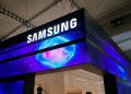 تابلوی بزرگ تبلیغاتی سامسونگ با نورپردازی آبی و بنفش و پسزمینه فضایی در نمایشگاه فناوری داخل سالن، همراه با لوگوی روشن SAMSUNG در بالای غرفه