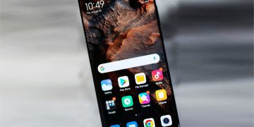 نمای جلوی یک گوشی هوشمند با حاشیه‌های بسیار باریک و تصویر پس‌زمینه انتزاعی نارنجی و مشکی.