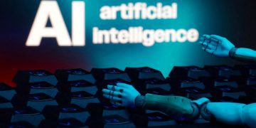 دست رباتیک در حال تعامل با صفحه‌کلید کامپیوتر در مقابل عبارت Artificial Intelligence؛ نمایش مفهوم اتوماسیون، هوش مصنوعی و فناوری‌های پیشرفته