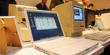 لپتاپ مکبوک در کنار کامپیوترهای مکینتاش قدیمی روی میز نمایش، نشاندهنده تکامل طراحی و پیشرفت فناوری رایانههای اپل در گذر زمان